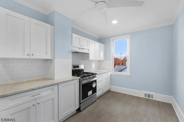 a kitchen with granite countertop white cabinets and stainless steel appliances