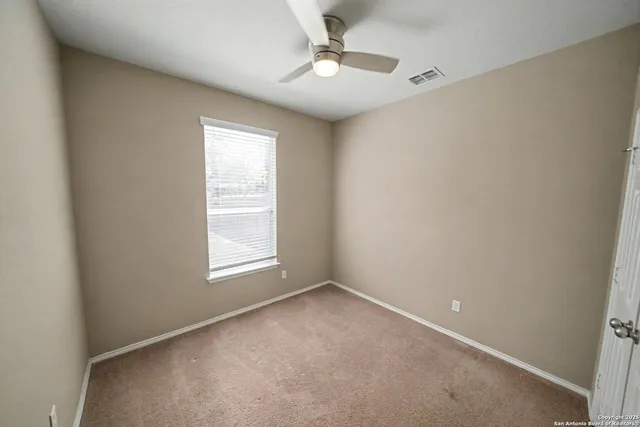 an empty room with a window and ceiling fan