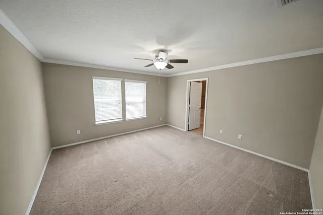 an empty room with chandelier fan and windows