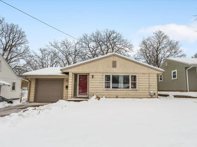 a front view of house with yard and trees in the background