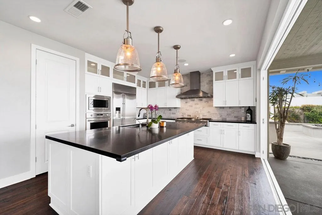 896 Channel Island Drive Encinitas, CA 92024 - Photo 14 of 51 a kitchen with stainless steel appliances granite countertop a sink dishwasher a refrigerator and white cabinets with wooden floor