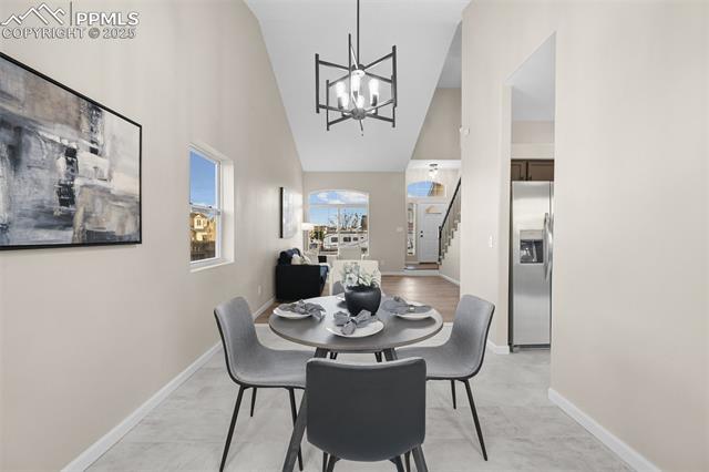 5428 Rondo Way Colorado Springs, CO 80911 - Photo 8 of 43 Dining space with high vaulted ceiling, a chandelier, and stairway