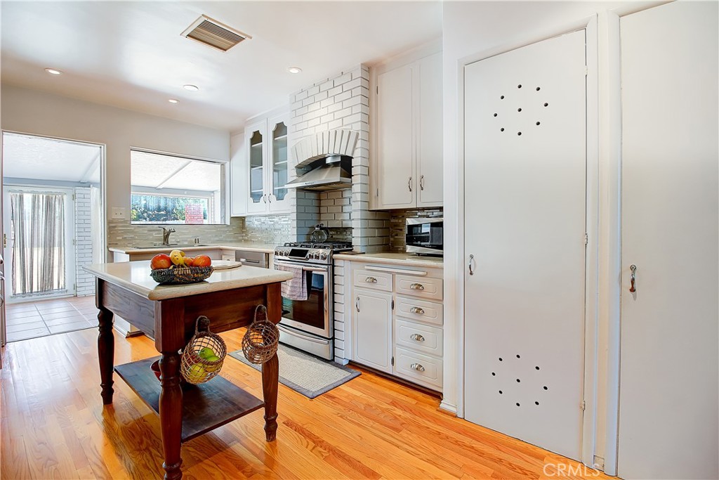 4662 Sierra Street Riverside, CA 92504 - Photo 17 of 41 a kitchen with stainless steel appliances a refrigerator a stove a sink dishwasher and white cabinets with wooden floor