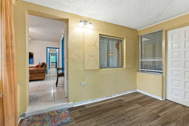 a view of a livingroom with wooden floor a chandelier and a bathroom