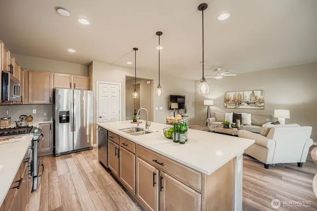 a kitchen with stainless steel appliances kitchen island granite countertop a sink a stove and a wooden floor