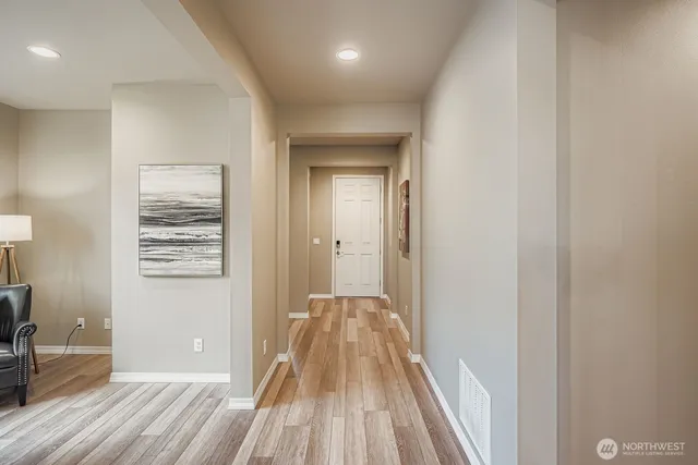 a view of a hallway with wooden floor and a bathroom