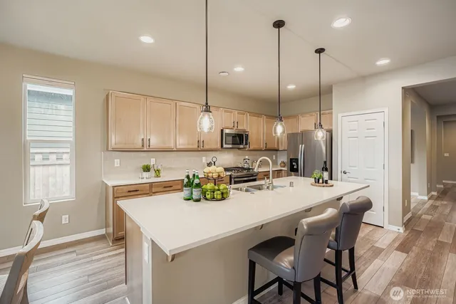 a kitchen with a stove a refrigerator a sink a dining table and chairs with wooden floor