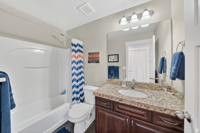 7872 Farm House Lane Midvale, UT 84047 - Photo 22 of 39 Second Bathroom featuring a white bathtub, a single vanity with a granite-style countertop, a rectangular mirror, a dark wood-finish cabinet, and wood-finish flooring