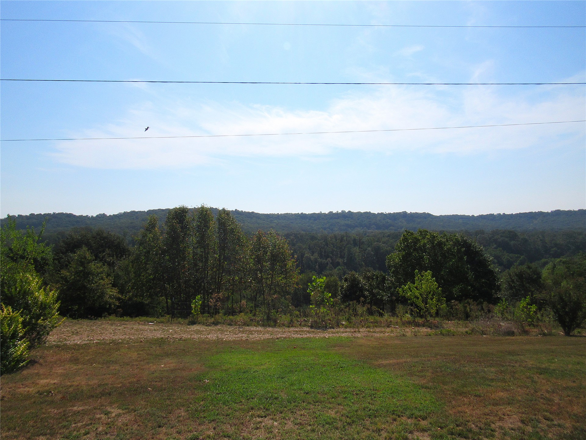 86048 South 4735 Road Stilwell, OK 74960 - Photo 33 of 66 Expansive outdoor space featuring a partial manicured lawn, established landscaping, and distant tree-covered hills
