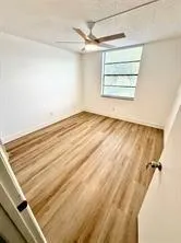 a view of a room with a ceiling fan and wooden floor