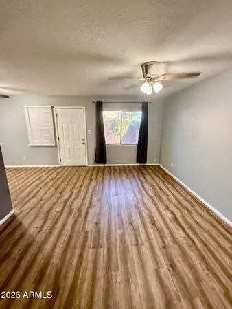a view of empty room with wooden floor and fan