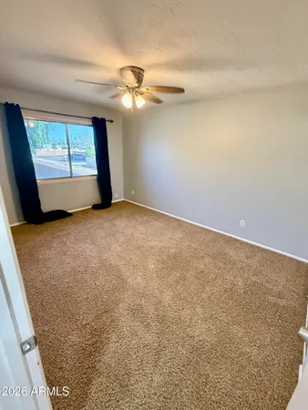 an empty room with a chandelier fan and windows