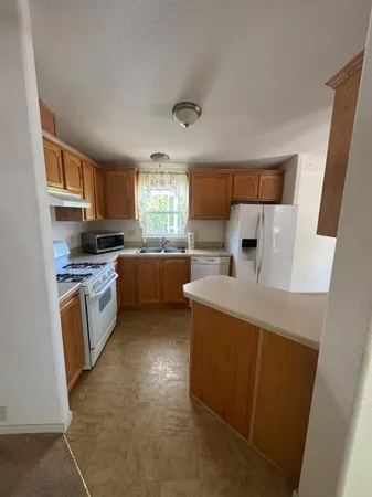 a kitchen with a sink a stove top oven a refrigerator and a window