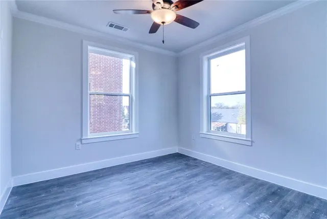 an empty room with wooden floor chandelier fan and windows