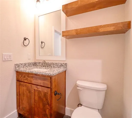 a bathroom with a granite countertop toilet and a sink