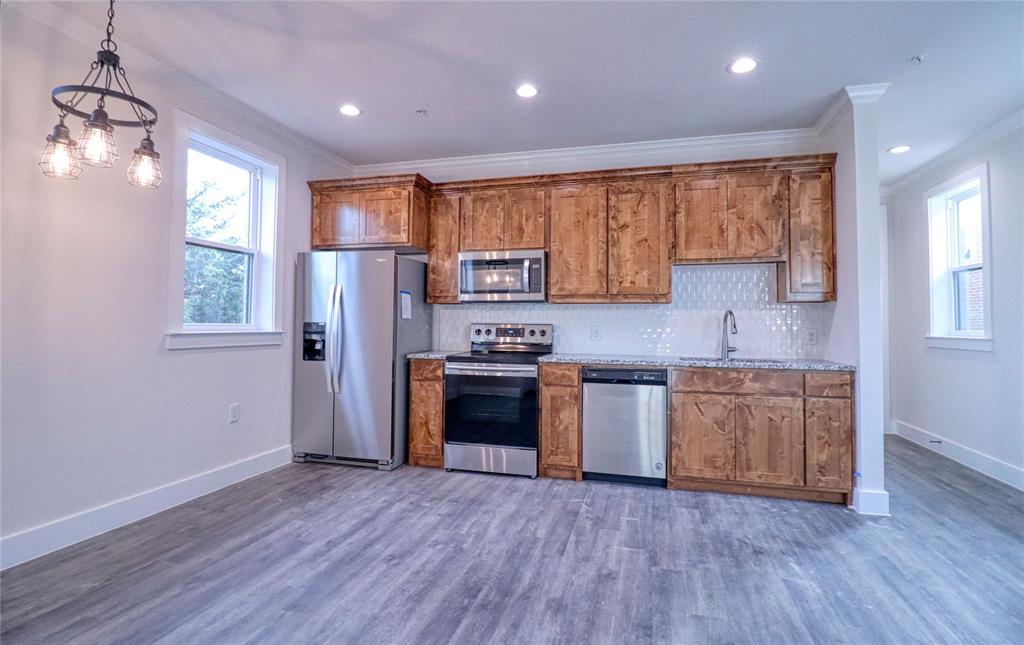 525 George Hopper Road, Unit 210 Midlothian, TX 76065 - Photo 5 of 20 a kitchen with granite countertop wooden floors stainless steel appliances a sink and a window