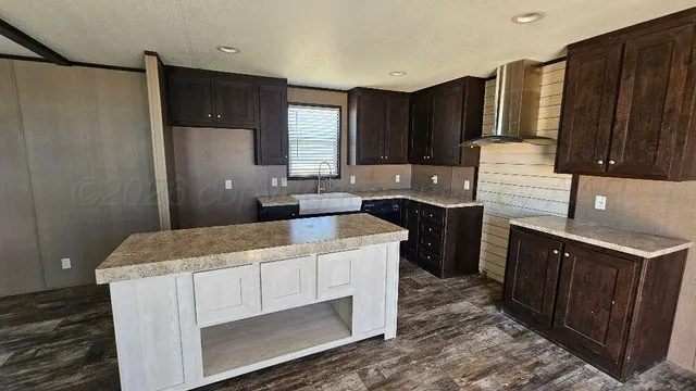 a kitchen with stainless steel appliances kitchen island granite countertop a refrigerator and a stove top oven