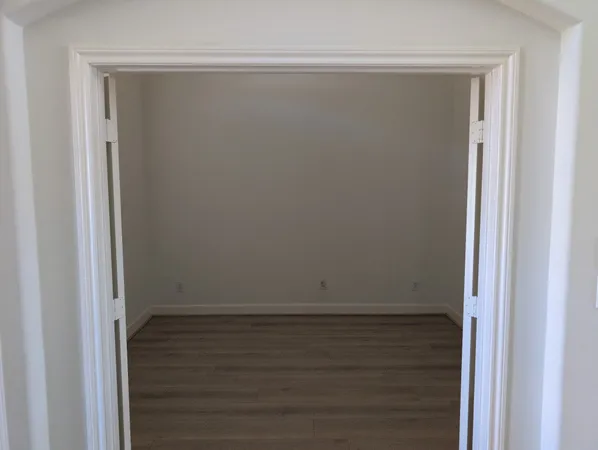 a view of an empty room with a window and wooden floor