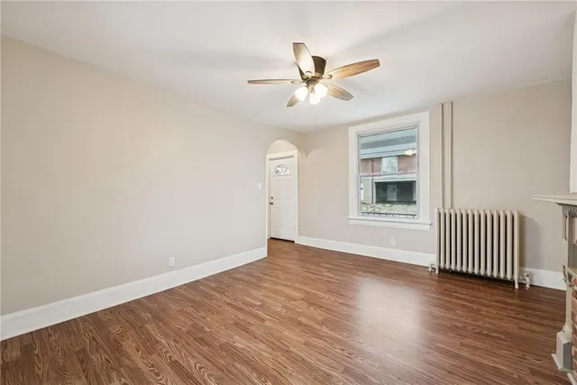 an empty room with wooden floor fan and windows