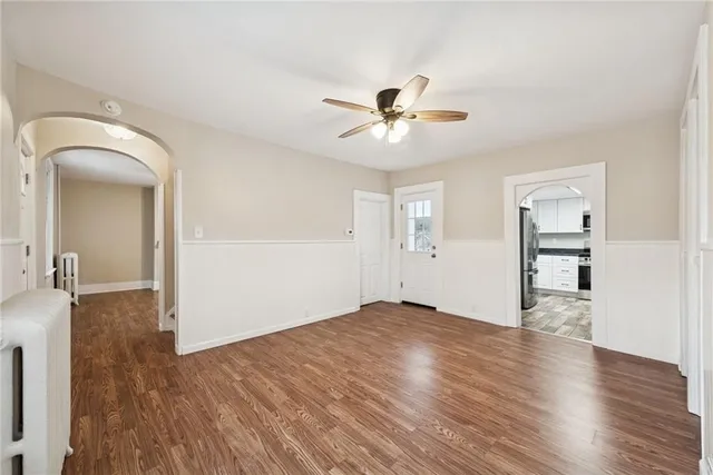 a view of empty room with wooden floor and ceiling fan