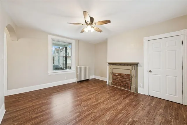 an empty room with wooden floor closet and windows