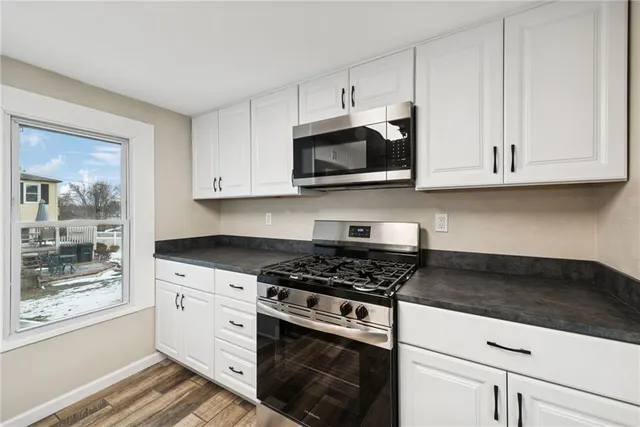 a kitchen with granite countertop white cabinets and stainless steel appliances