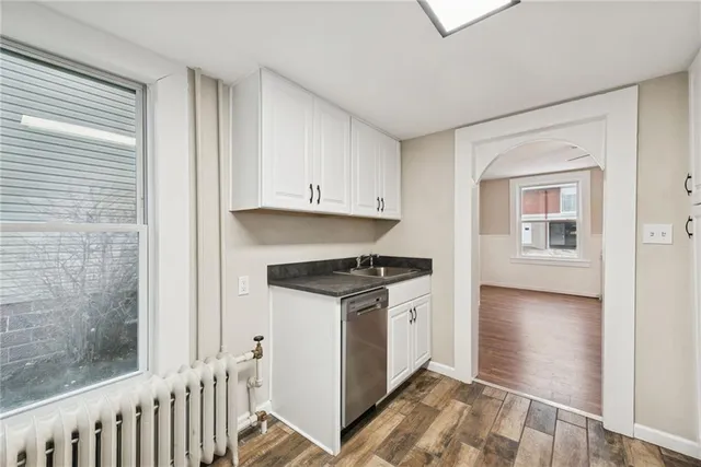 a kitchen with granite countertop a stove and white cabinets