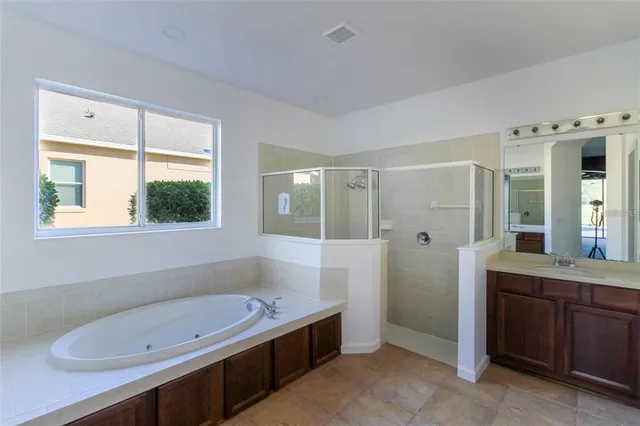 a bathroom with a tub a sink and a large window