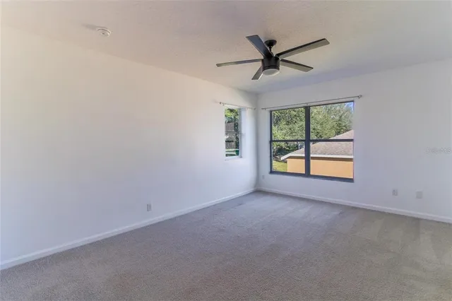 an empty room with windows and ceiling fan