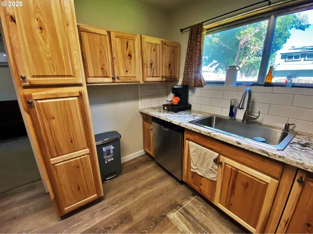 a kitchen with stainless steel appliances granite countertop a refrigerator a sink a stove a washer dryer and a window