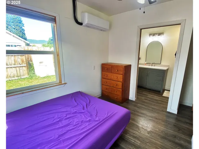 a bedroom with a bed and a dresser next to a window
