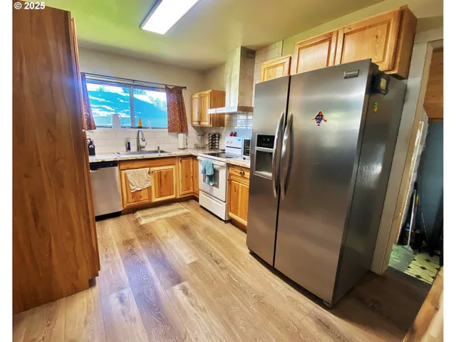 a kitchen with stainless steel appliances granite countertop a refrigerator a sink and a stove