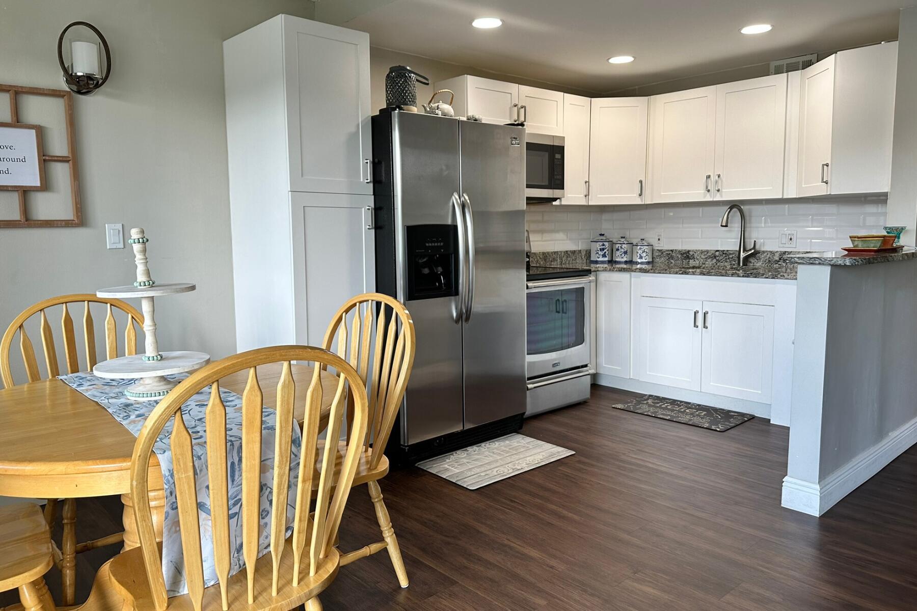 a kitchen with stainless steel appliances granite countertop a kitchen island a stove a refrigerator a stove a sink with a dining table and chairs