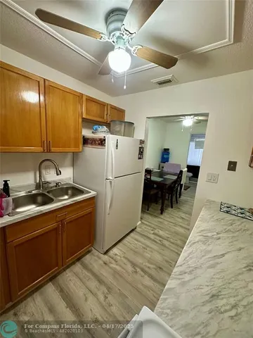 a kitchen with stainless steel appliances granite countertop a sink a stove a refrigerator cabinets and chairs