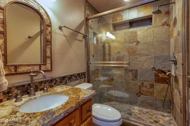 a bathroom with a granite countertop sink toilet a mirror and shower