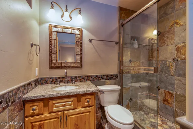 a bathroom with a granite countertop toilet sink and mirror