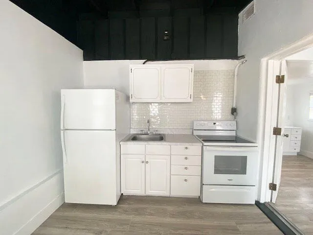 a kitchen with white cabinets and white appliances