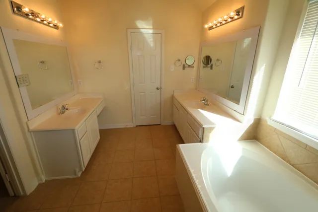 a bathroom with a tub a sink and a large mirror