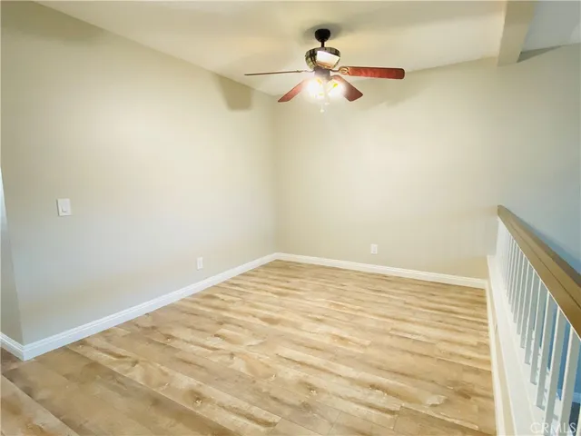 a view of a room with a ceiling fan and wooden floor