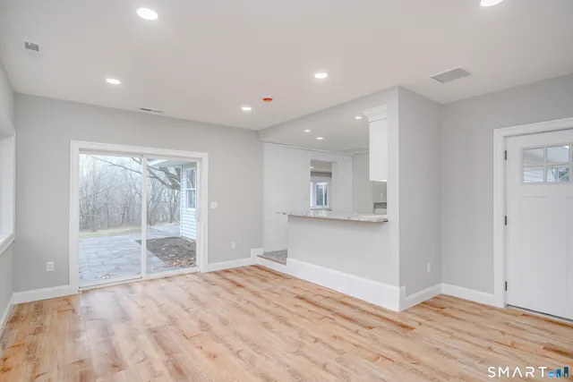 a view of a dining room and livingroom with furniture wooden floor a rug a potted plant and a painting