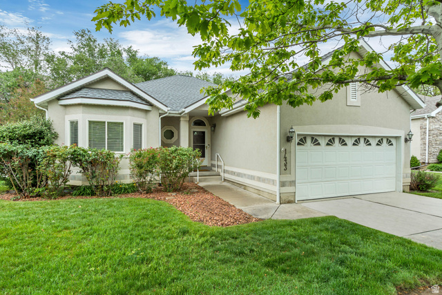 Stucco exterior residence featuring a front-facing attached garage with decorative windows and sconce lighting