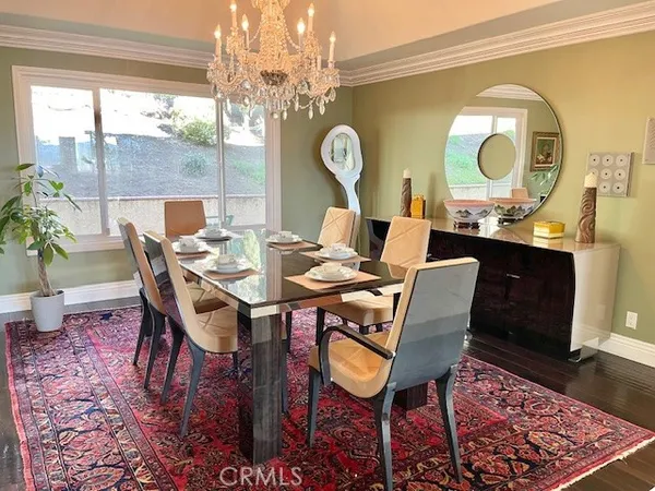 a dining room with chandelier and wooden floor