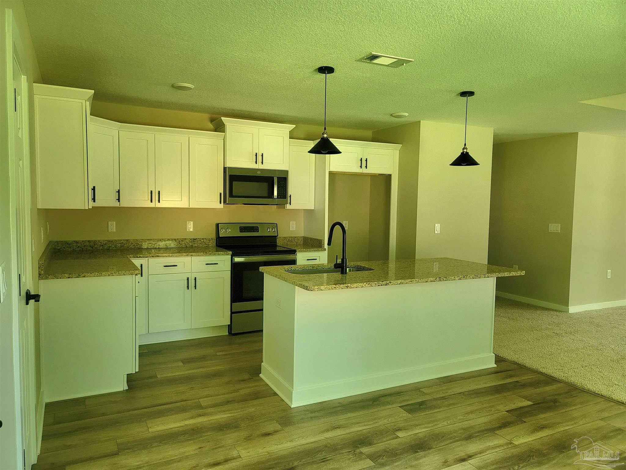 3030 Ferris Drive Navarre, FL 32566 - Photo 16 of 40 a kitchen with kitchen island white cabinets and stainless steel appliances