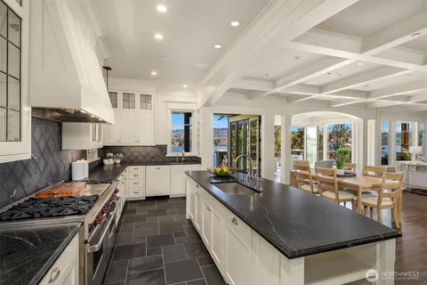 a kitchen with stainless steel appliances granite countertop a stove a sink dishwasher a dining table and chairs with wooden floor
