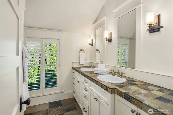 a bathroom with a granite countertop sink and a window