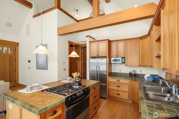 a kitchen with stainless steel appliances kitchen island granite countertop a stove refrigerator and cabinets