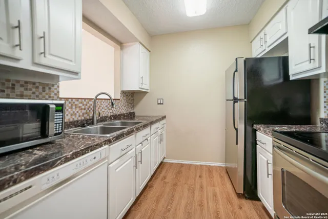 a kitchen with granite countertop a sink stove and refrigerator