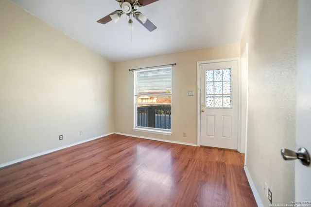 an empty room with wooden floor fan and windows
