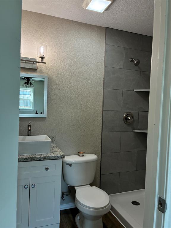 5066 East Highway 199 Springtown, TX 76082 - Photo 11 of 15 Bathroom in bedroom with a textured wall, vanity, a stall shower, a textured ceiling, and vinyl finished floors