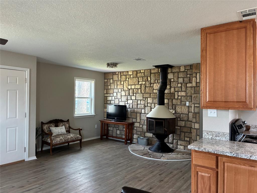 5066 East Highway 199 Springtown, TX 76082 - Photo 8 of 15 Living area with a wood stove, vinyl flooring and a textured ceiling